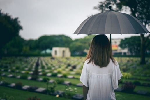 sad little girl standing in graveyard